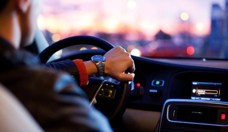 Person with a hand on the steering wheel of a car. 